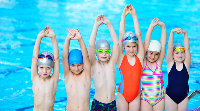 happy children kids group at swimming pool class learning to swim